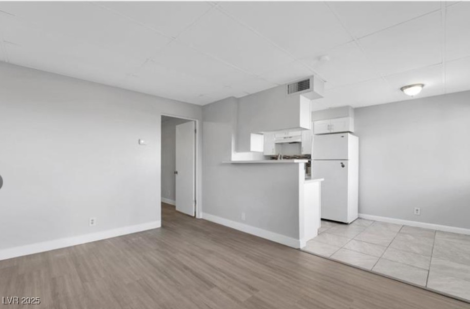 239 West Cleveland Avenue, Unit 2 Las Vegas, NV 89102 - Photo 2 of 13 Unfurnished living room featuring light wood-style floors and a drop ceiling