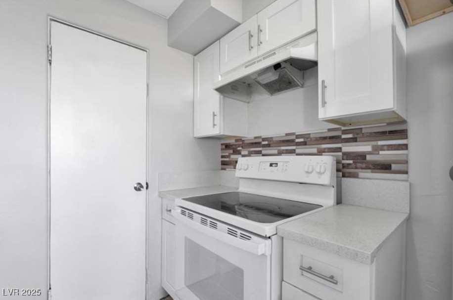 239 West Cleveland Avenue, Unit 2 Las Vegas, NV 89102 - Photo 6 of 13 Kitchen featuring white electric stove, white cabinets, tasteful backsplash, light countertops, and under cabinet range hood