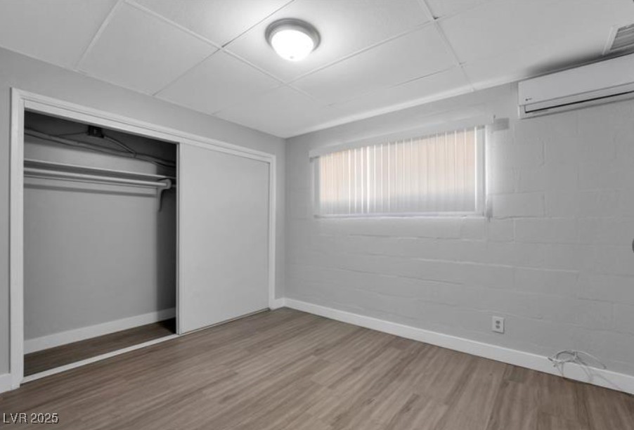 239 West Cleveland Avenue, Unit 2 Las Vegas, NV 89102 - Photo 7 of 13 Unfurnished bedroom featuring a drop ceiling, light wood-type flooring, an AC wall unit, and a closet