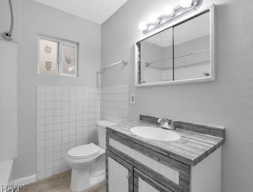 239 West Cleveland Avenue, Unit 2 Las Vegas, NV 89102 - Photo 9 of 13 Half bathroom featuring vanity, light wood-style flooring, and tile walls