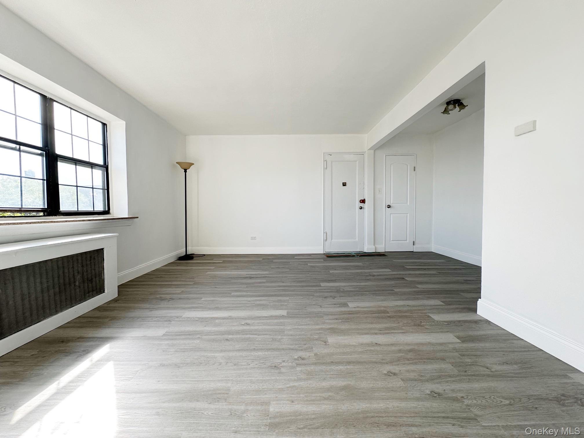 78-16 147th Street, Unit 3C Queens, NY 11367 - Photo 1 of 16 Empty room featuring radiator heating unit and light wood-type flooring