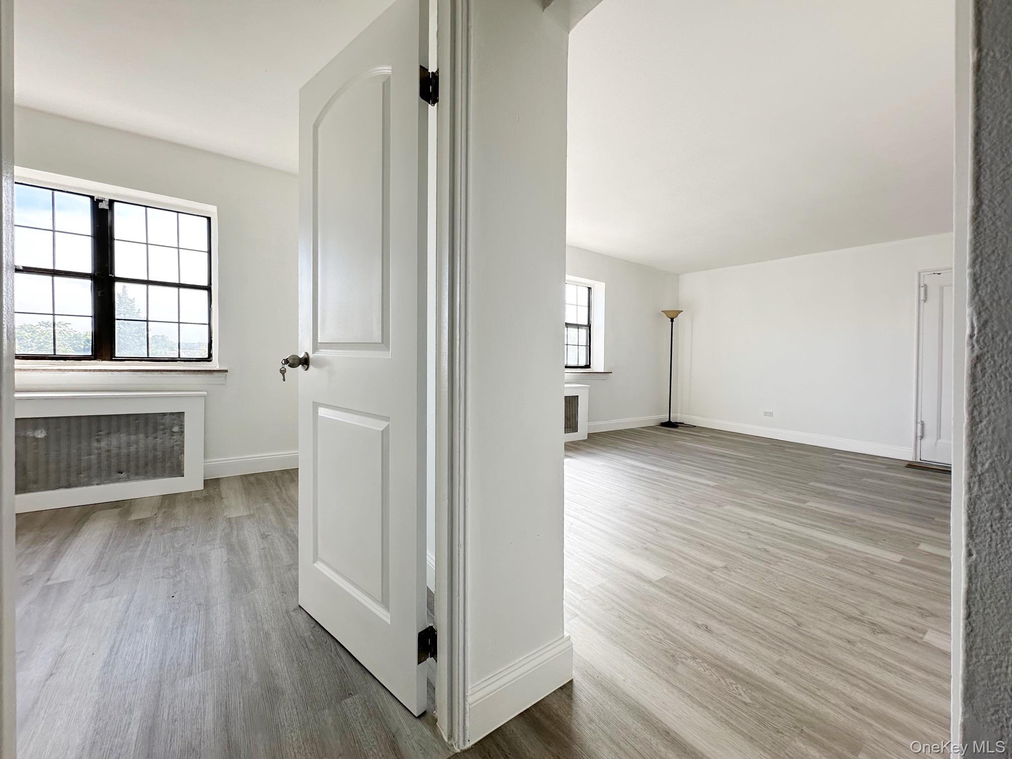 78-16 147th Street, Unit 3C Queens, NY 11367 - Photo 11 of 16 Hall with radiator heating unit and light wood-style floors