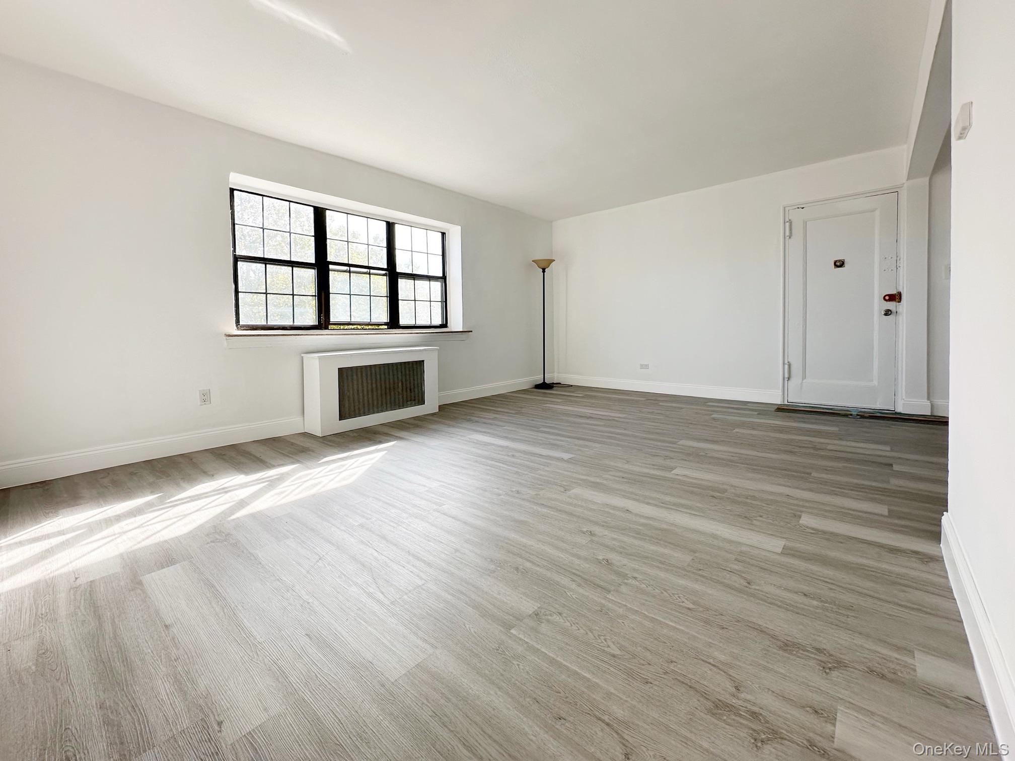 78-16 147th Street, Unit 3C Queens, NY 11367 - Photo 12 of 16 Empty room featuring radiator heating unit and light wood-style flooring