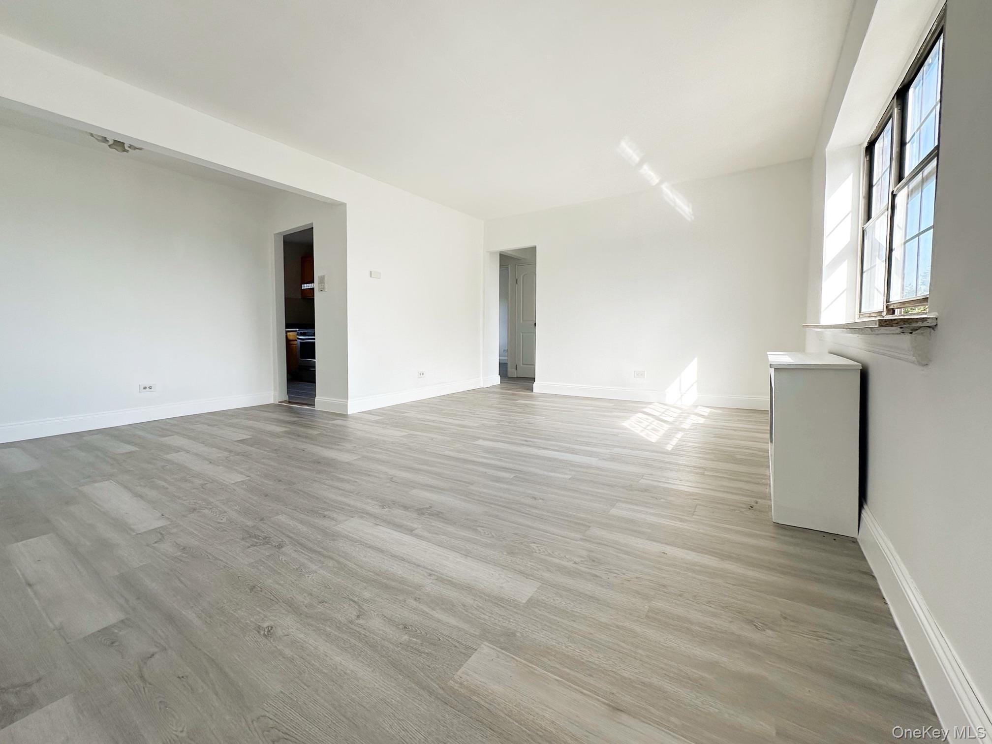 78-16 147th Street, Unit 3C Queens, NY 11367 - Photo 9 of 16 Empty room with light wood-style floors and baseboards