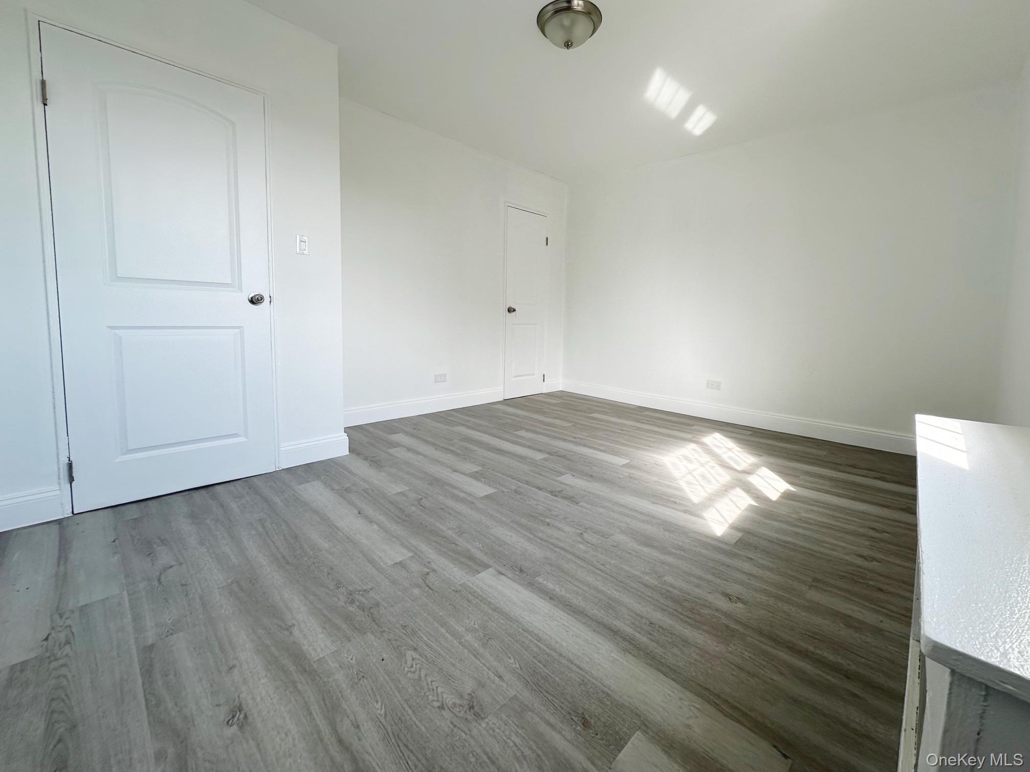 78-16 147th Street, Unit 3C Queens, NY 11367 - Photo 10 of 16 Spare room featuring wood finished floors and baseboards