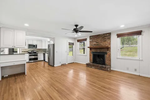 a view of an empty room with kitchen and a window