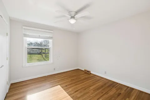 an empty room with a window and a ceiling fan