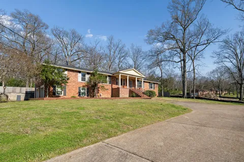 a front view of a house with a yard and trees
