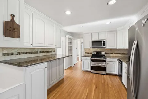 a kitchen with kitchen island granite countertop white cabinets and stainless steel appliances
