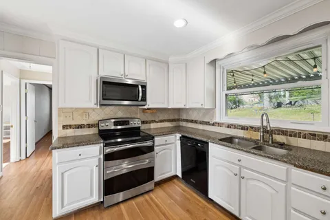 a kitchen with granite countertop a stove a sink and a microwave