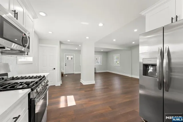 a kitchen with stainless steel appliances granite countertop a refrigerator a stove and a sink with wooden floor