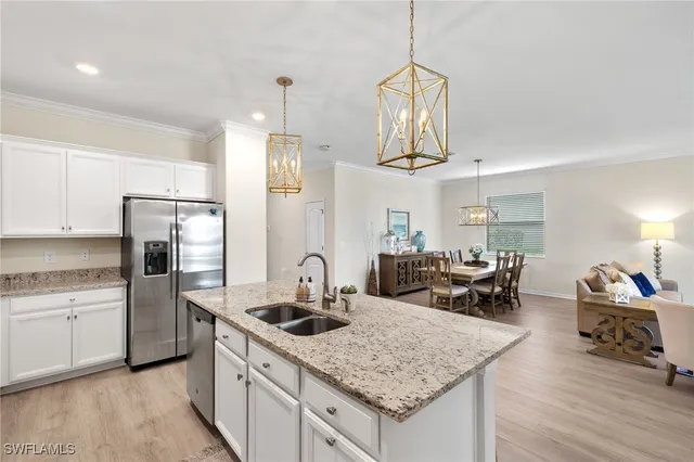 a kitchen with stainless steel appliances granite countertop a sink dishwasher a refrigerator white cabinets and wooden floor