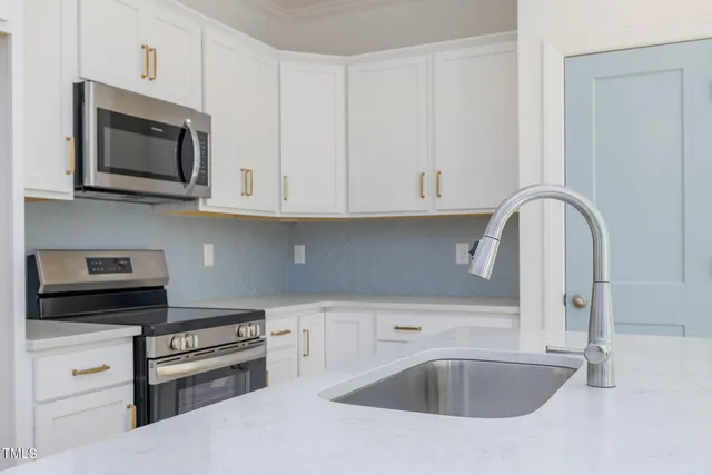 a kitchen with white cabinets and stainless steel appliances