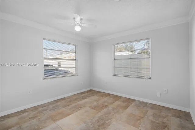 an empty room with windows and ceiling fan
