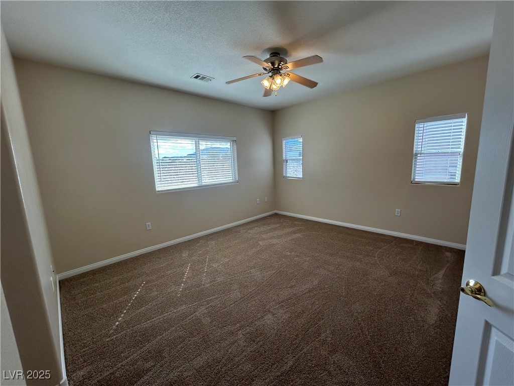 9303 Gilcrease Avenue, Unit 1131 Las Vegas, NV 89149 - Photo 11 of 36 Spare room featuring dark carpet, plenty of natural light, a ceiling fan, and a textured ceiling