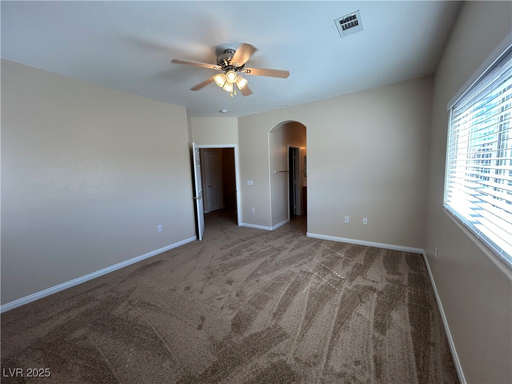 9303 Gilcrease Avenue, Unit 1131 Las Vegas, NV 89149 - Photo 14 of 36 Spare room featuring light carpet, arched walkways, and a ceiling fan