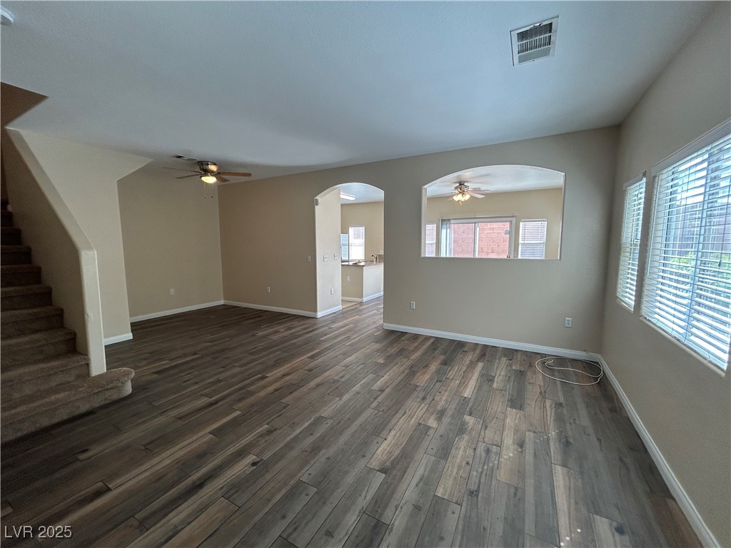 9303 Gilcrease Avenue, Unit 1131 Las Vegas, NV 89149 - Photo 2 of 36 Unfurnished living room featuring ceiling fan, arched walkways, dark wood-style flooring, and stairs