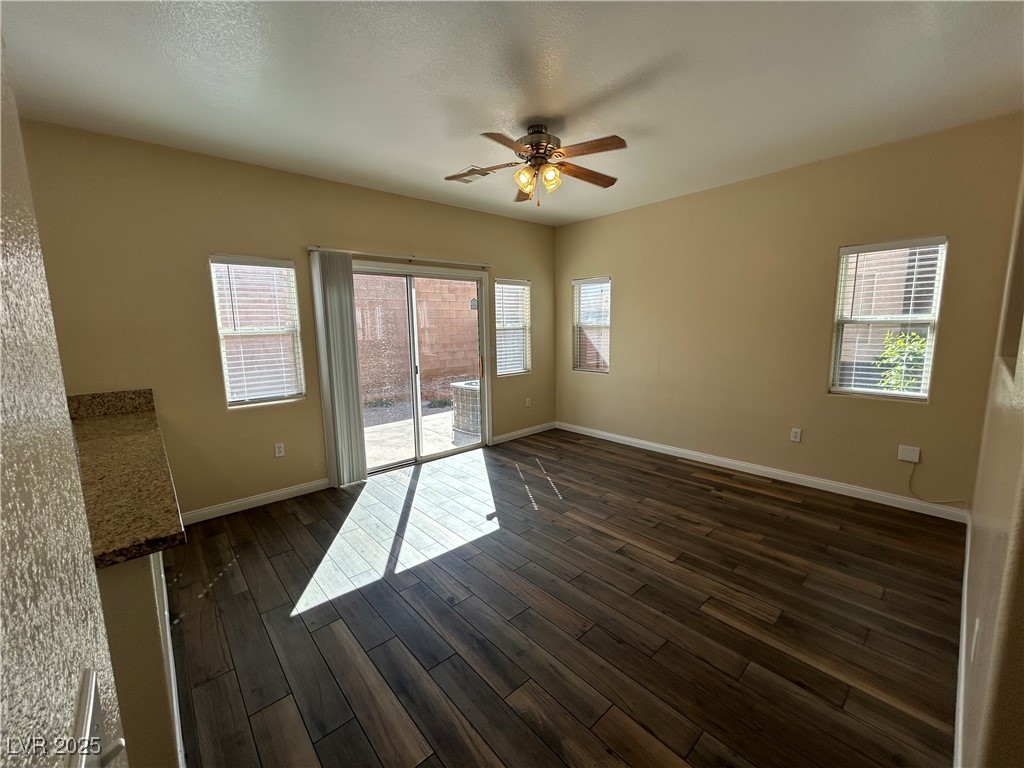 9303 Gilcrease Avenue, Unit 1131 Las Vegas, NV 89149 - Photo 4 of 36 Unfurnished room with plenty of natural light, a ceiling fan, and dark wood-style flooring