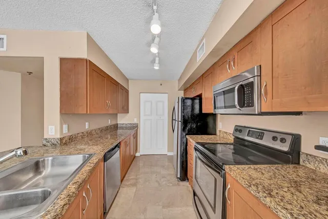 a kitchen with stainless steel appliances granite countertop a sink stove and refrigerator