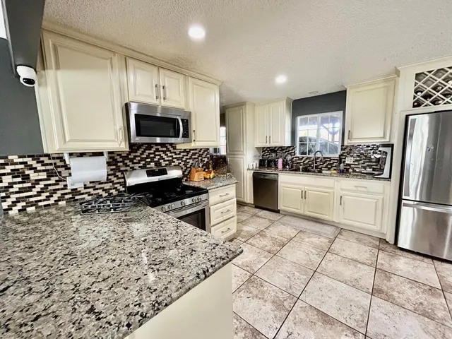 a kitchen with stainless steel appliances a stove a sink a microwave a refrigerator and cabinets