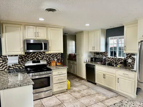 a kitchen with stainless steel appliances granite countertop a stove a sink and a microwave