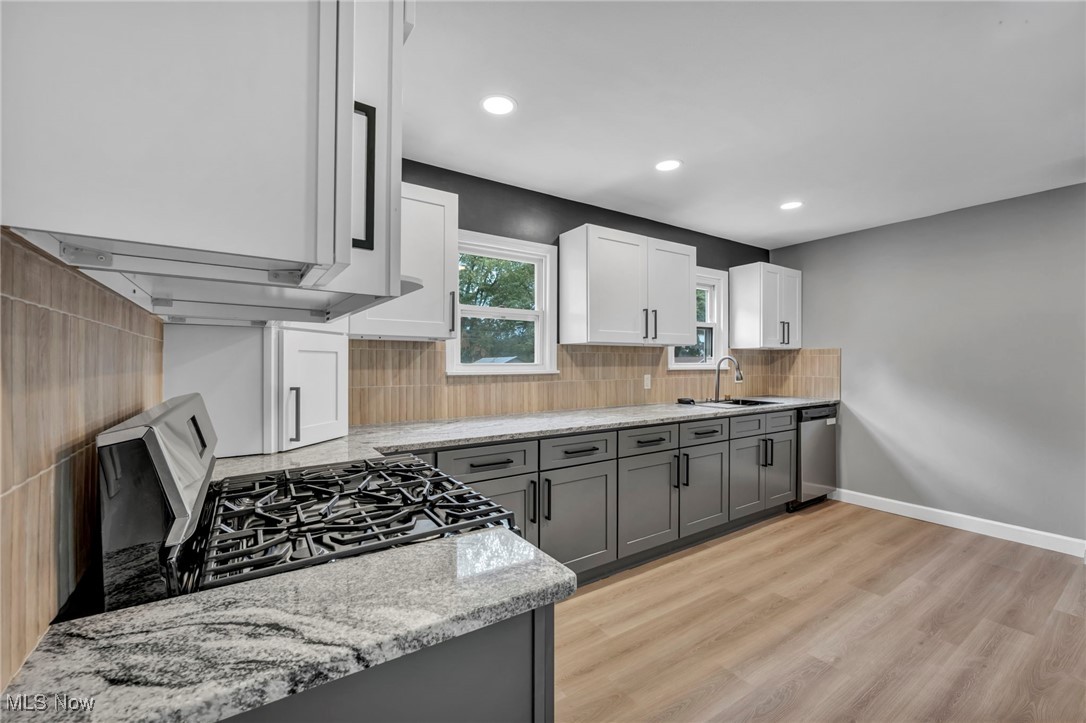 20202 Sumpter Road Cleveland, OH 44128 - Photo 8 of 46 Kitchen with gray cabinetry, light stone countertops, black range with gas cooktop, white cabinetry, and light wood-style flooring