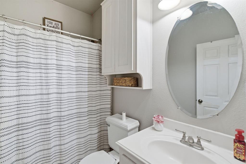 1889 Greenwood Road, Unit RES Weatherford, TX 76088 - Photo 7 of 11 a bathroom with a toilet a sink and mirror