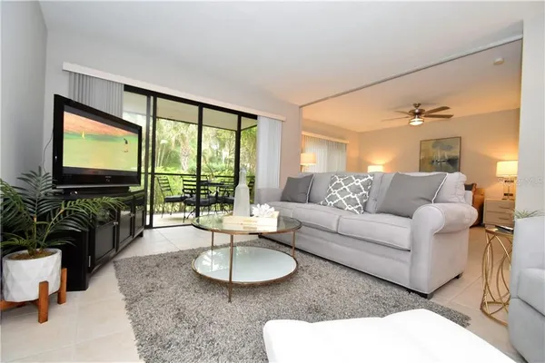 a living room with furniture a flat screen tv and a large window