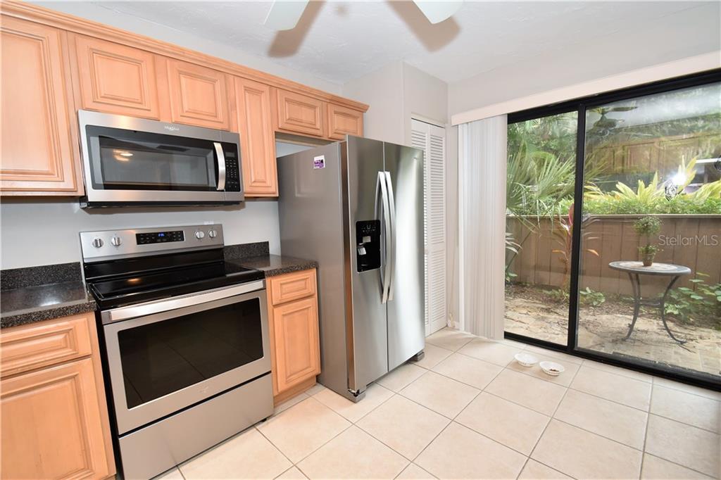 1667 Brookhouse Circle, Unit BR128 Sarasota, FL 34231 - Photo 9 of 38 a kitchen with granite countertop a stove top oven and a refrigerator