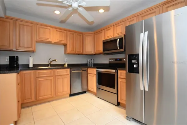 a kitchen with stainless steel appliances granite countertop a refrigerator oven a sink dishwasher and white cabinets with wooden floor