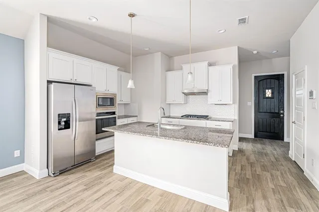 a kitchen with stainless steel appliances granite countertop a refrigerator a sink and a stove