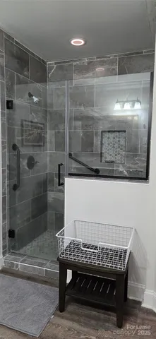 a bathroom with a glass shower door and a wooden table