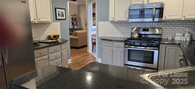 a kitchen with granite countertop a stove top oven a sink a counter space and cabinets