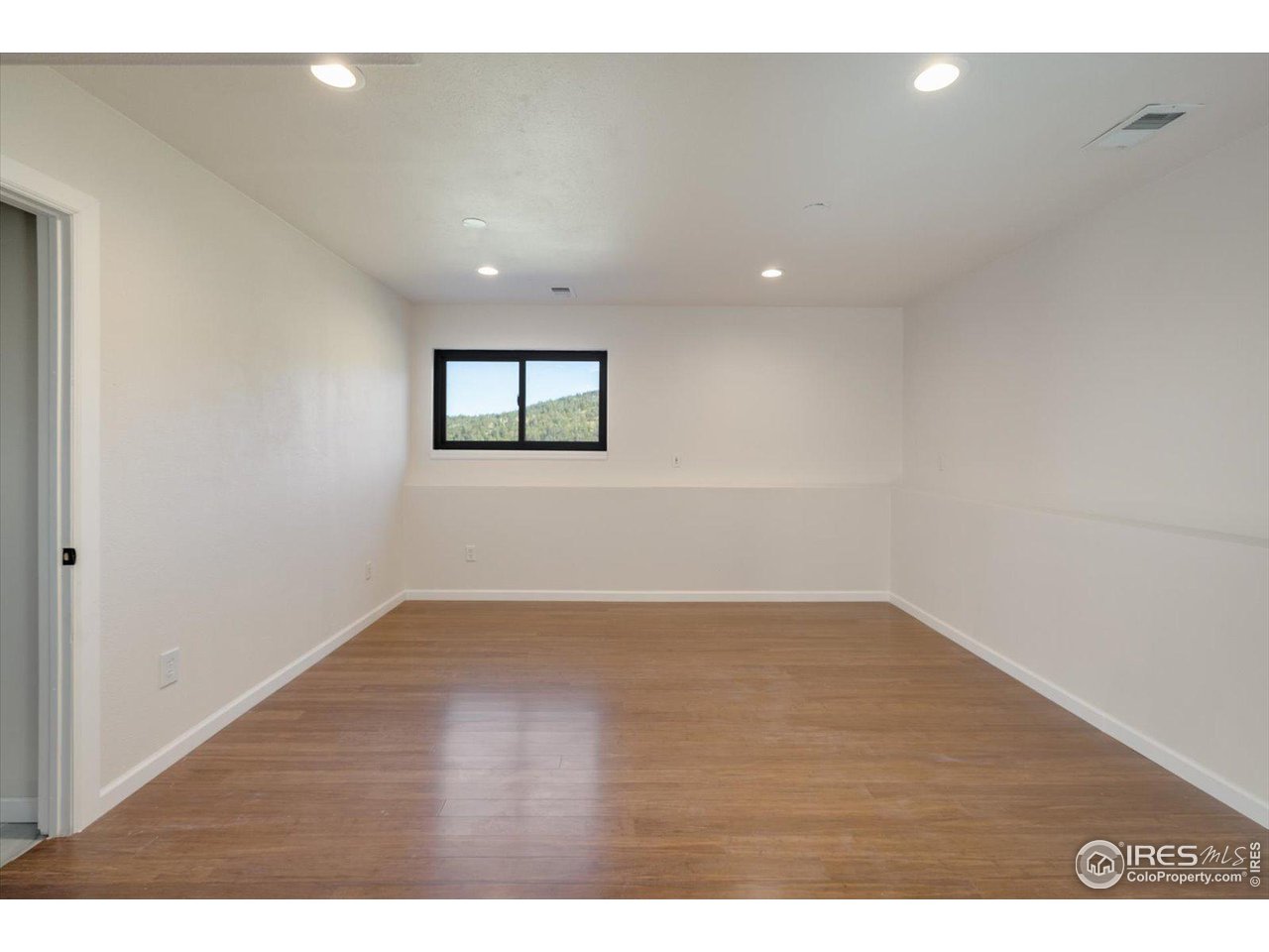 147 Makah Lane Lyons, CO 80540 - Photo 18 of 39 a view of an empty room with wooden floor and a window