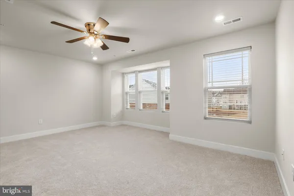 an empty room with chandelier fan and windows