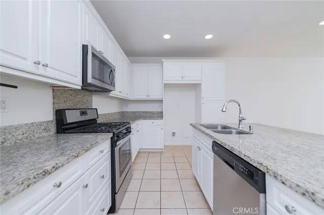a kitchen with granite countertop stainless steel appliances a sink stove top oven and cabinets