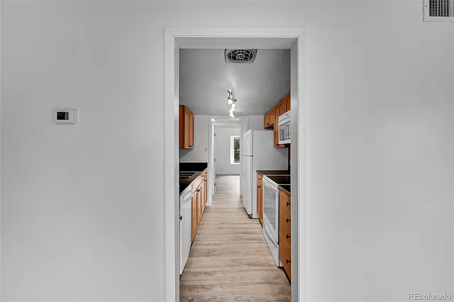 a hallway with white cabinets and stainless steel appliances