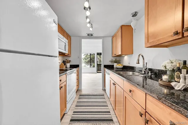 a kitchen with granite countertop stainless steel appliances a sink a refrigerator a counter top space and cabinets