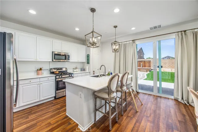 a kitchen with stainless steel appliances granite countertop a stove top oven a sink dishwasher and a refrigerator with wooden floor