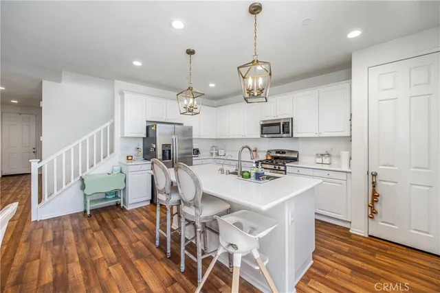 an open kitchen with wooden floor and stainless steel appliances