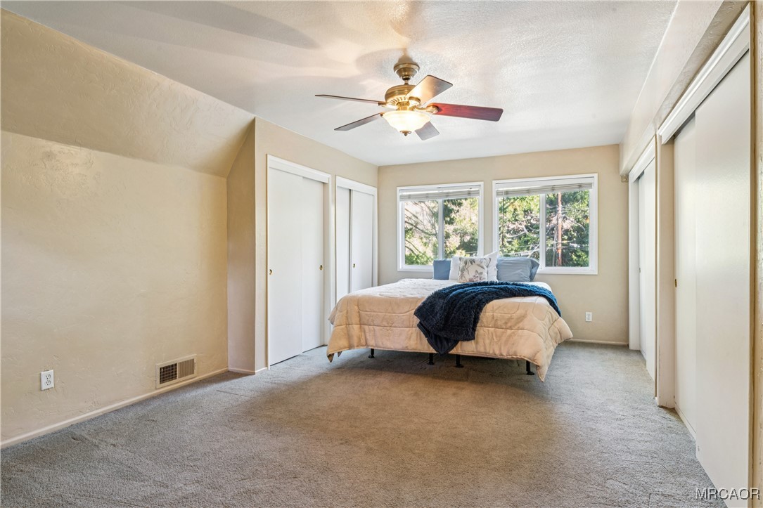 296 Massive Road Lake Arrowhead, CA 92352 - Photo 17 of 43 a spacious bedroom with a bed and a chandelier