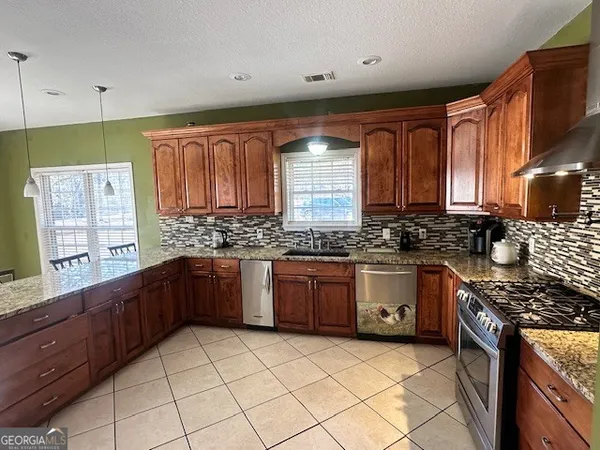 a kitchen with stainless steel appliances granite countertop a stove a sink and a microwave