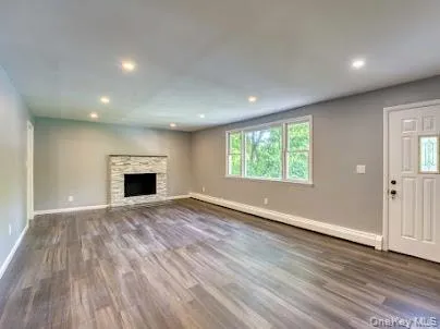 an empty room with wooden floor fireplace and windows
