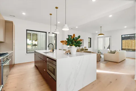a large white kitchen with a large island oven a stove and a sink