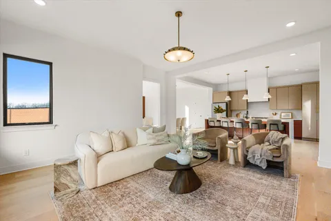 a living room with furniture kitchen view and a chandelier