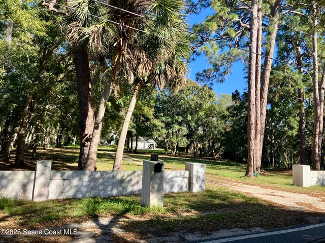 a view of a wooden house with a yard and large trees