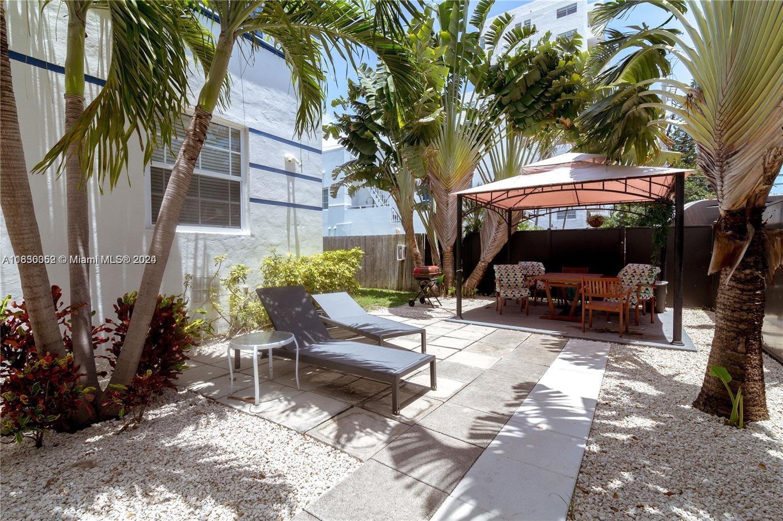 1241 13th Street, Unit 4 Miami Beach, FL 33139 - Photo 12 of 13 a view of a patio with table and chairs potted plants and a large tree