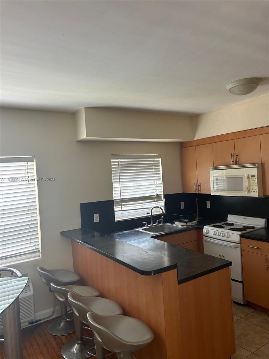 1241 13th Street, Unit 4 Miami Beach, FL 33139 - Photo 7 of 13 a kitchen with stainless steel appliances a sink a stove a refrigerator cabinets and dining table