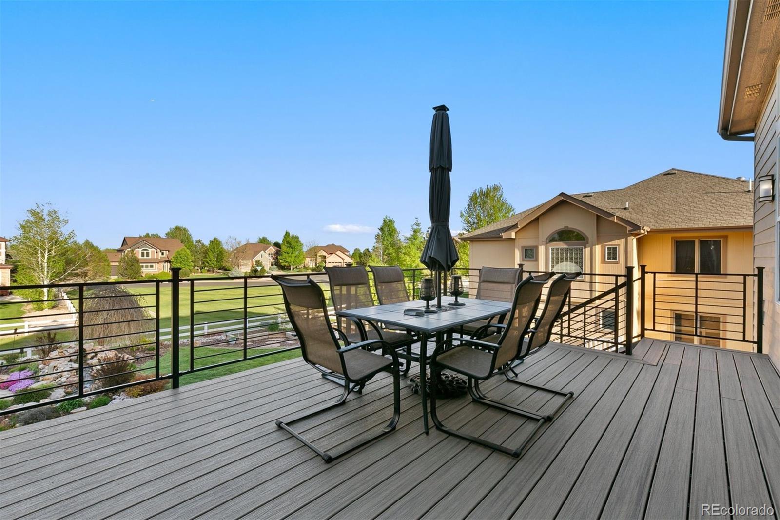 8440 Spinnaker Bay Drive Windsor, CO 80528 - Photo 35 of 36 a view of a roof deck with table and chairs a barbeque with wooden floor and fence