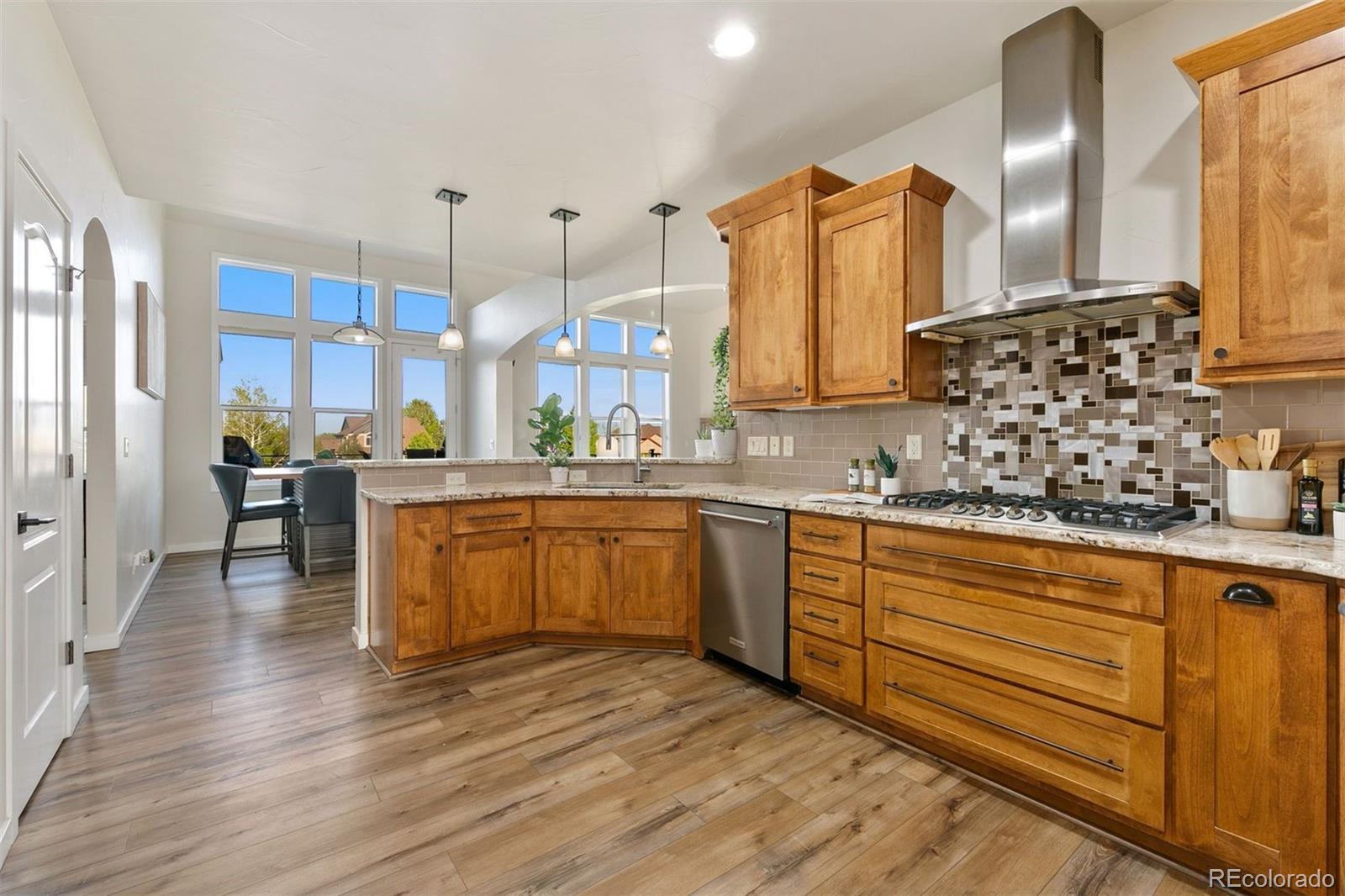8440 Spinnaker Bay Drive Windsor, CO 80528 - Photo 5 of 36 a kitchen with stainless steel appliances kitchen island granite countertop a sink a stove and wooden floors